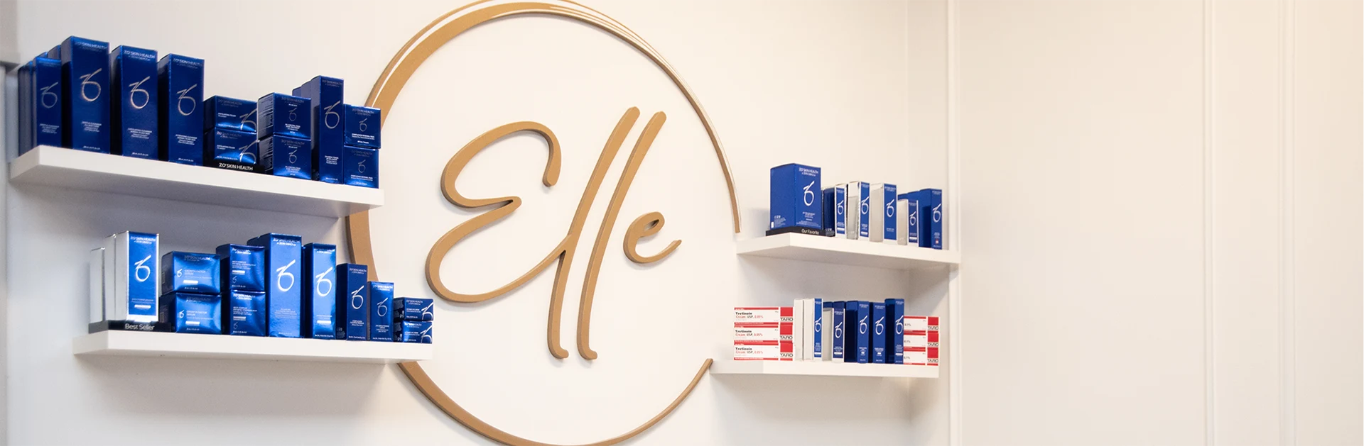 Elle Medical & Aesthetics logo on a wall beside shelves of skincare products