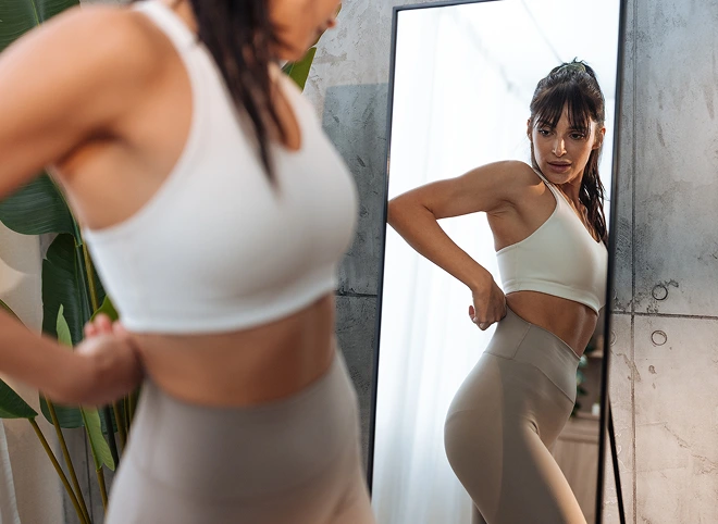 Fit woman checking her figure in a mirror