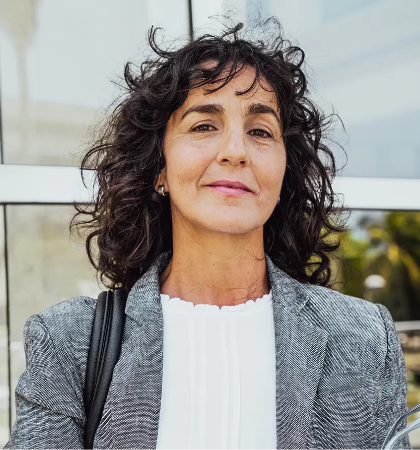 Confident mature woman with curly hair, representing facial and body contouring